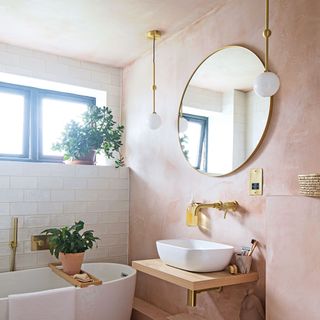 Pink bathroom with gold accents and small bath tub