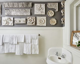 A powder room with white paint below the dado rail, grey paint above, and antique plaster panel decor