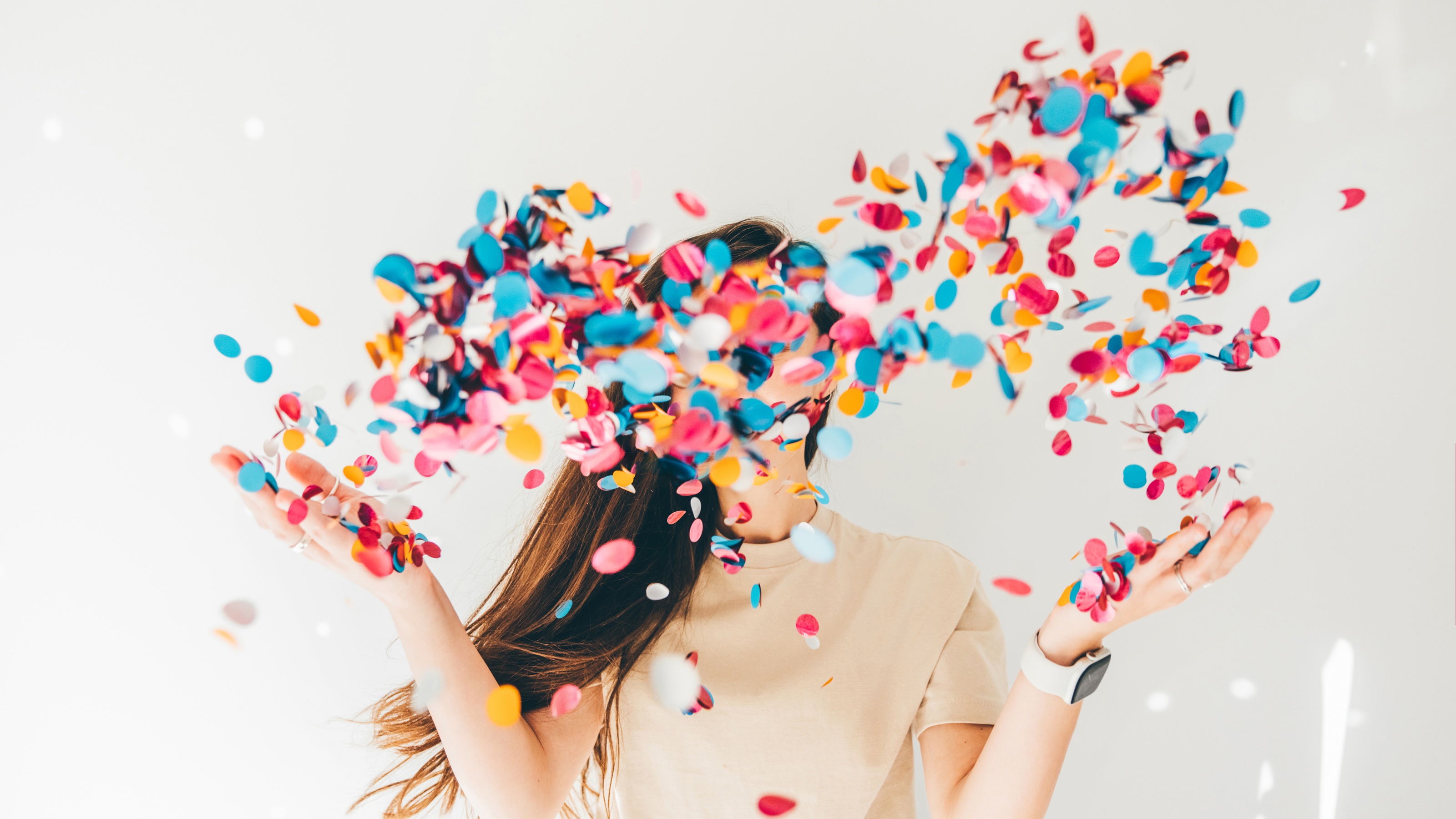 A woman throws confetti in the air that obscures her face.