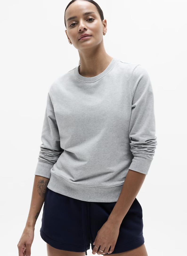 a model wearing an athleta sweatshirt in front of a plain backdrop