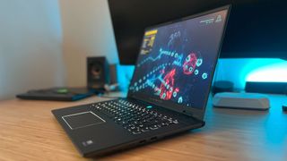 Alienware M16 R2 gaming laptop running Returnal while open on a wooden desk