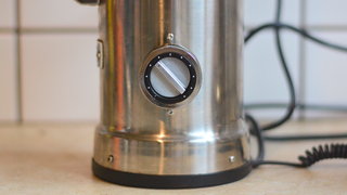 Image of the Aarke Coffee System – a stainless steel coffee bean grinder and drip coffee maker – positioned on a kitchen counter