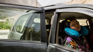 A woman using a Sea to Summit Aeros Ultralight Traveller Pillow dozes in the front seat of a car.