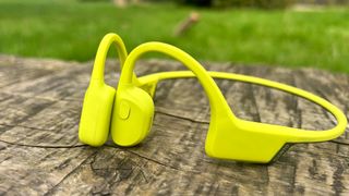 Suunto Sonic bone conduction headphones in lime on a wooden table