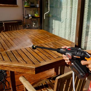 Worx pressure washer being used on wooden table outsdide