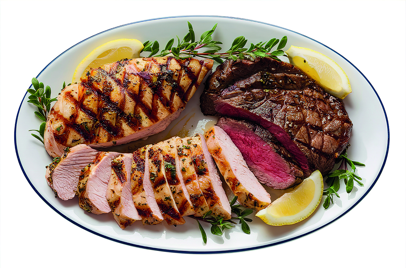 An isolated shot of a white plate containing sliced grilled chicken breast and a beef meat steak