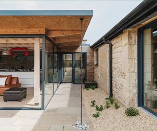 central linking extension to barn with timber roof, large sections of glazing and a rain chain