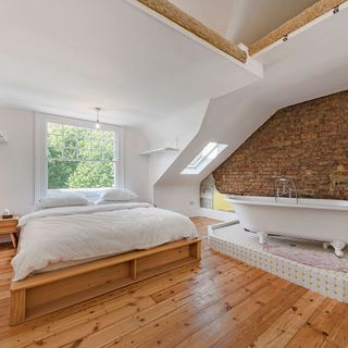 bedroom with free standing bath and wooden flooring