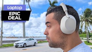 Man wearing Sony WH-1000XM5 wireless headphones outside with blue skies and palm trees in the background