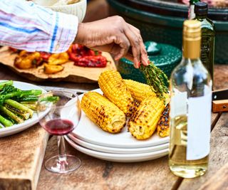 Grilled corn on a plate brushed with rosemary