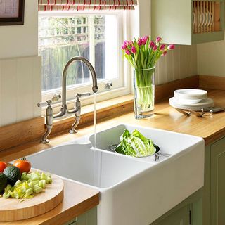 cream kitchen with soft green painted cupboards, wooden floors and countertops