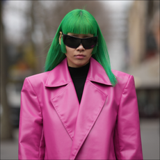 A guest wears black futurist sunglasses, a black turtleneck wool pullover, a neon pink shiny leather oversized blazer jacket, outside Palm Angels, during Paris Fashion Week - Womenswear Fall Winter 2023 2024, on March 05, 2023 in Paris, France. 