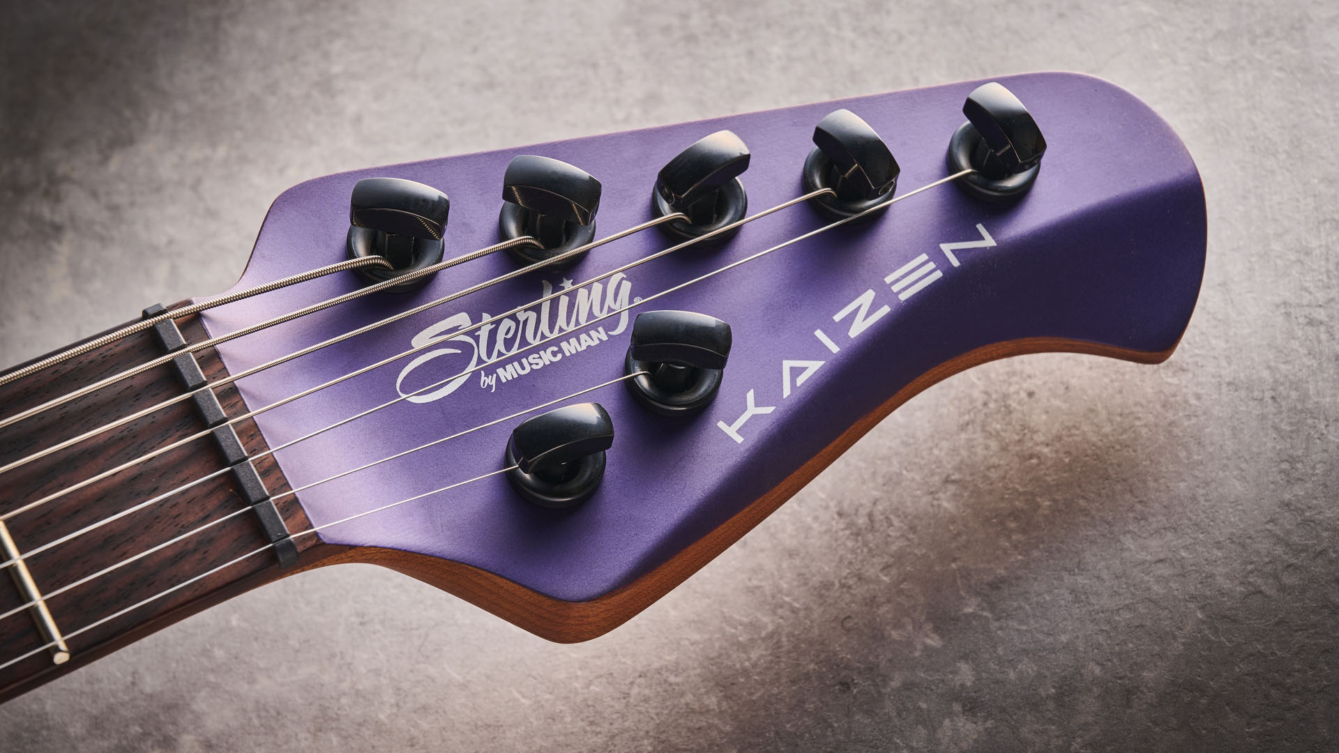 Sterling By Music Man Kaizen 7-string in Firemist Purple Satin, shot in close-up.