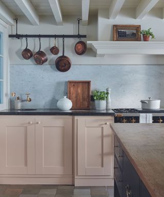 Pink kitchen with hanging copper pans and original wooden beams