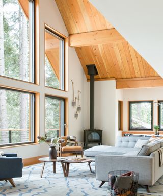 Corner fireplace in lodge style room with slanted wooden clad ceiling and neutral furnishings