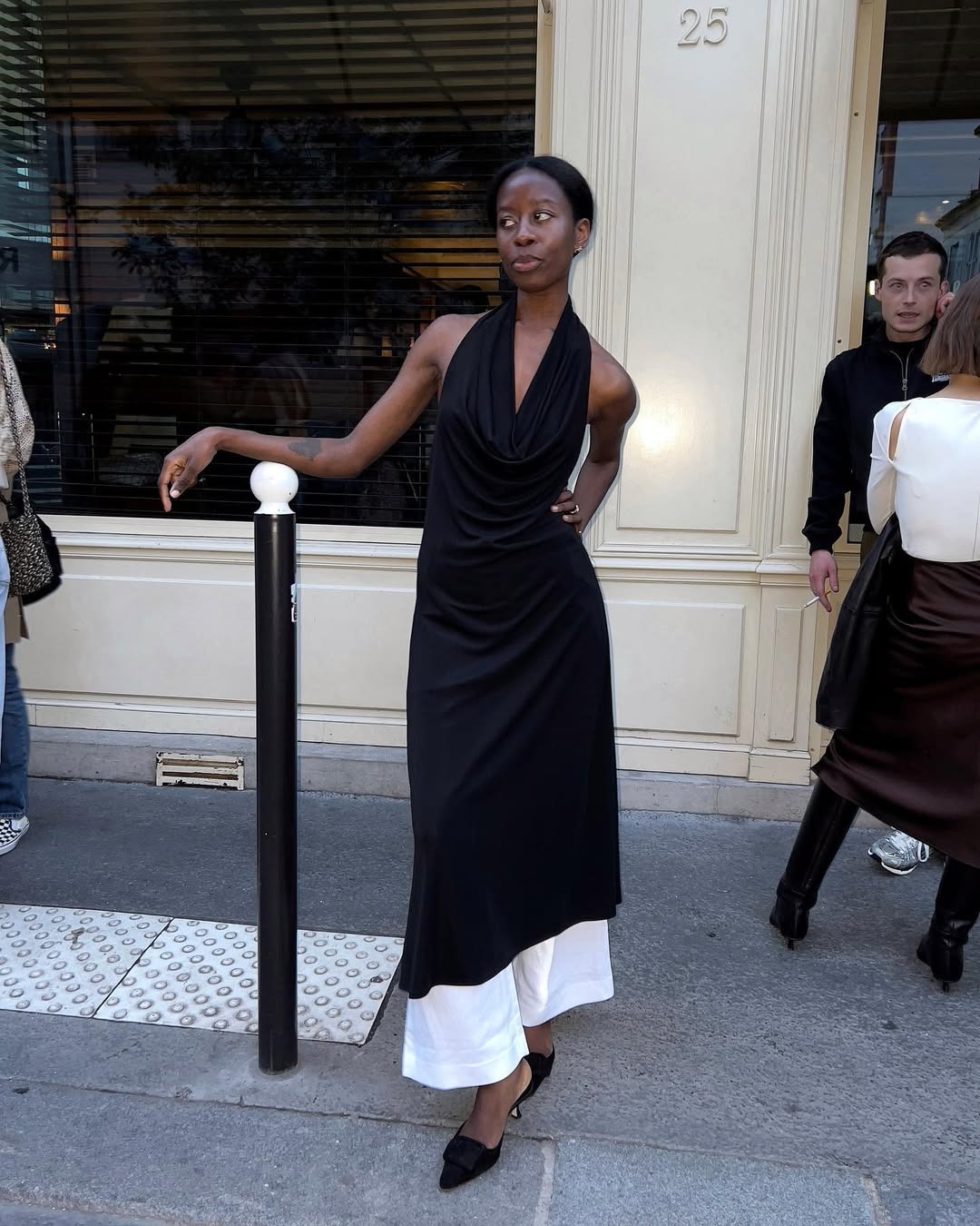 Influencer Sylvie Mus wears a halter dress with white pants and kitten heels.