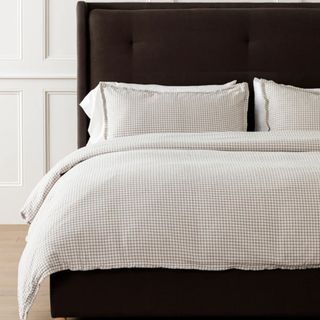 neutral plaid bedding on bed with dark headboard