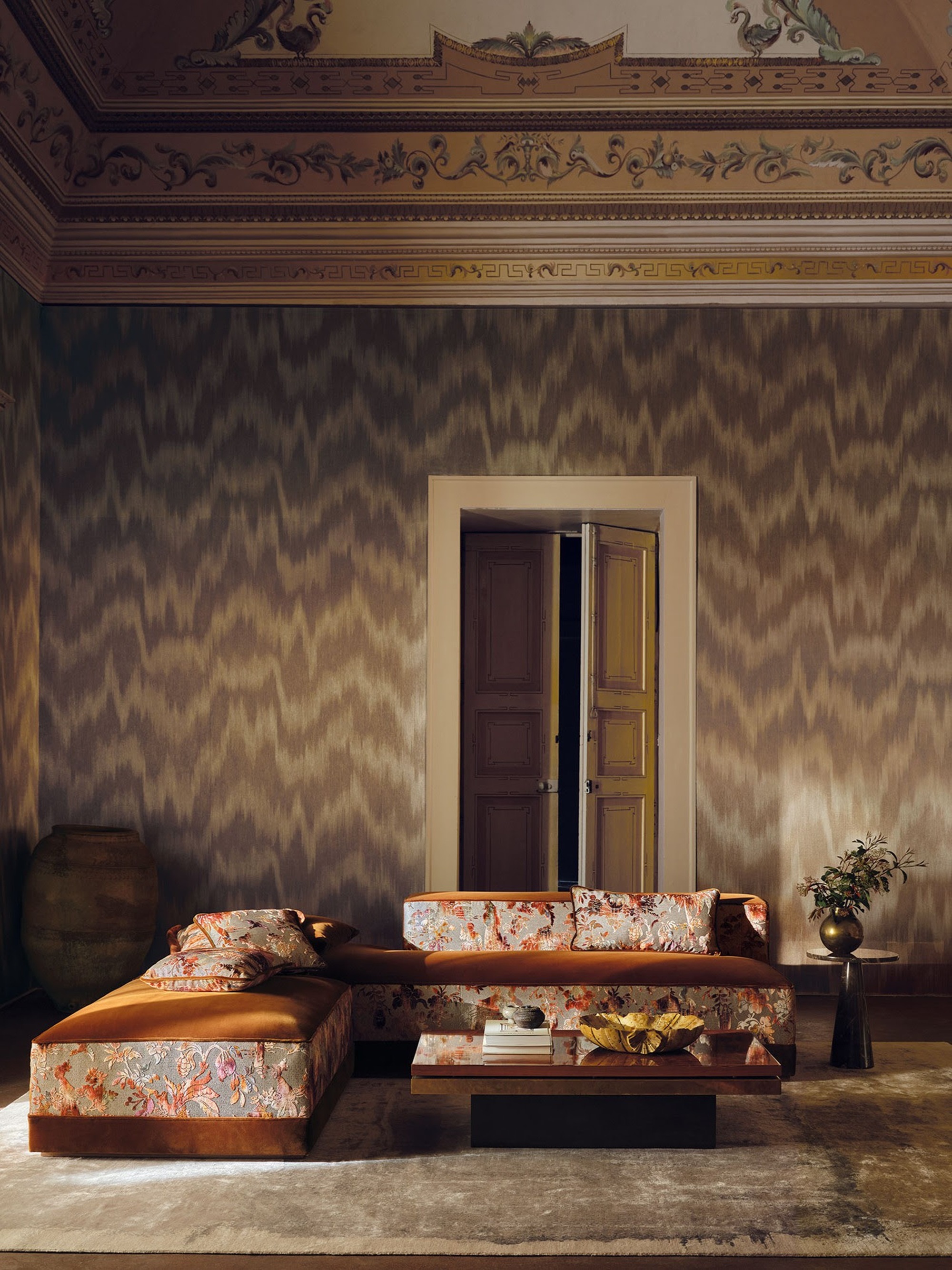 a room with a brown moire wallpaper and a low armless sofa