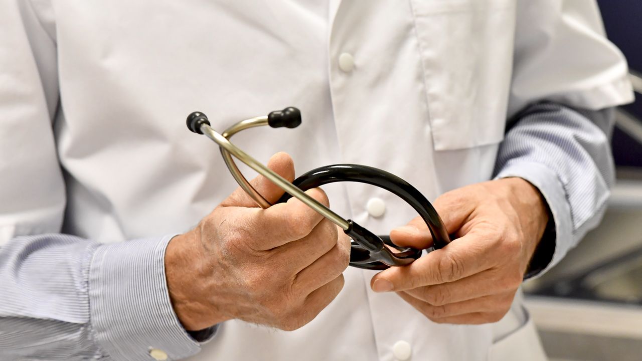 A GP holds a stethoscope