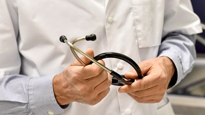 A GP holds a stethoscope