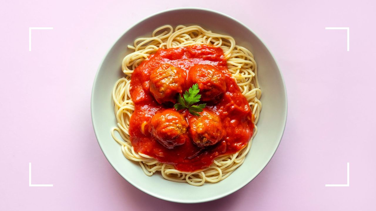 Bowl of spaghetti and meatballs on plain white china plate, representing the question of can menopause cause a loss of taste and smell