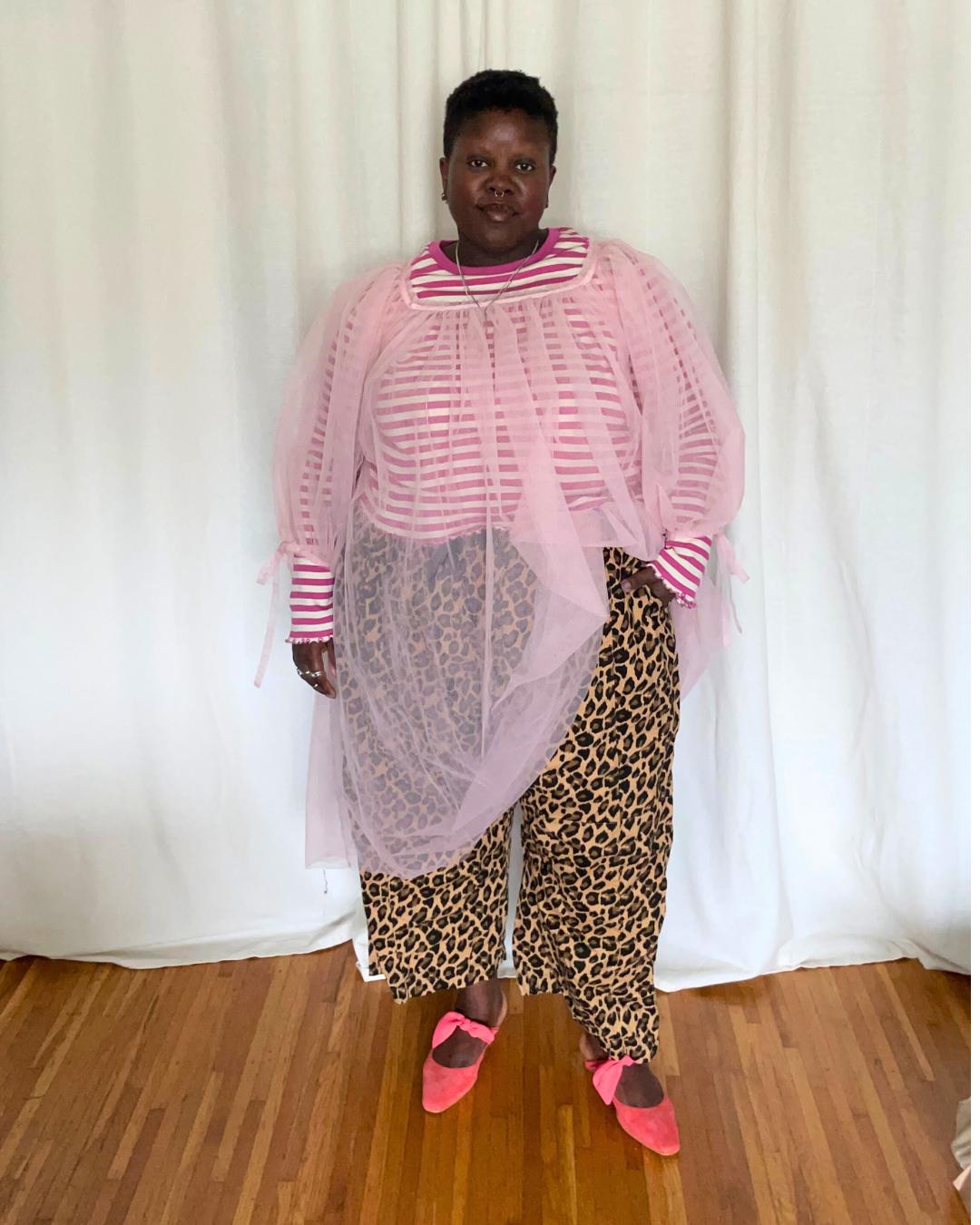 Lydia Okello wearing a sheer pink dress over a striped top and leopard pants