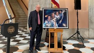 a man in a suit in front of a mural of astronauts and rockets