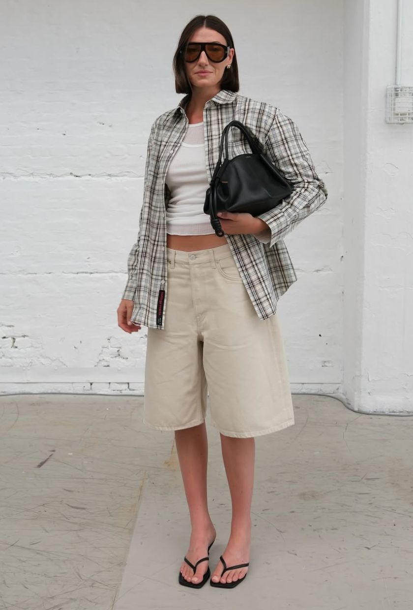 @sarahlouiseblythe wears a sage green flannel, baby t-shirt, beige Bermuda shorts, and black sandals