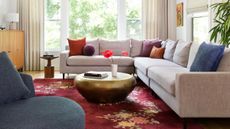 A living room with a large grey corner sofa, Persian-style carpet and brass coffee table