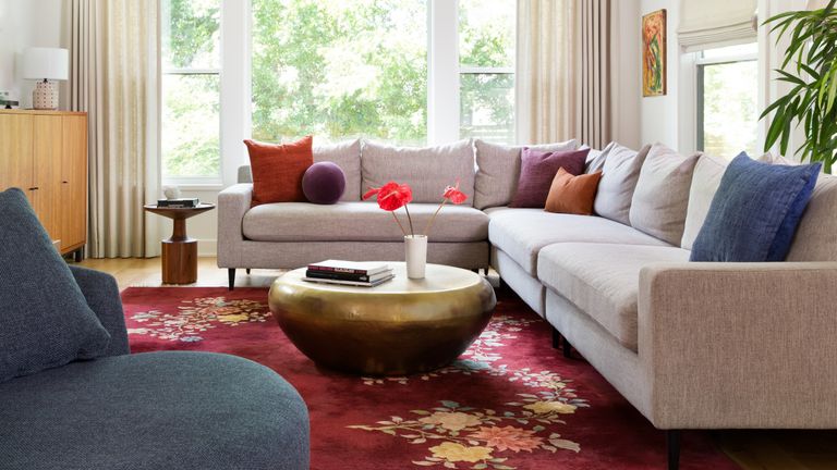 A living room with a large grey corner sofa, Persian-style carpet and brass coffee table
