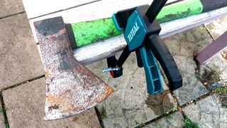 Close up of axe attached to wooden table top with clamp