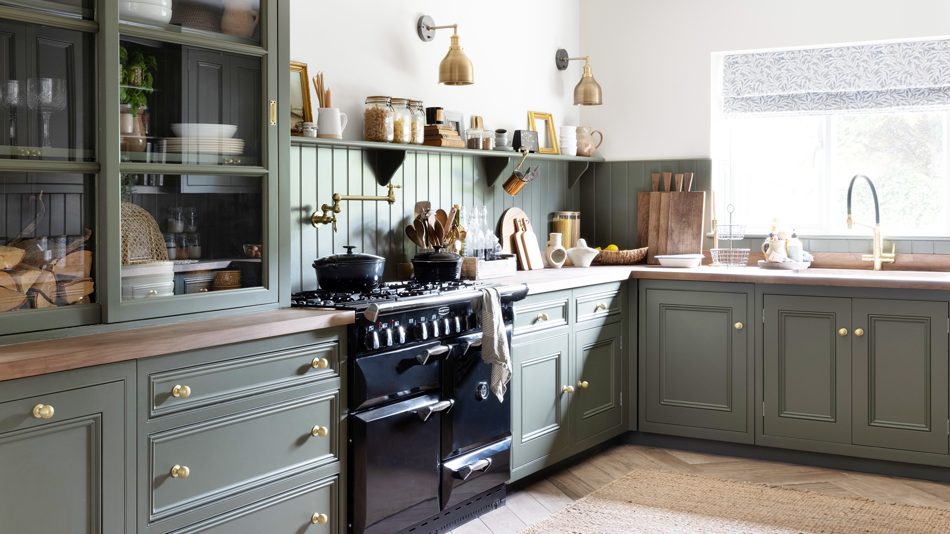 green secondhand kitchen with brass handles with black range cooker dresser and window with sink area 