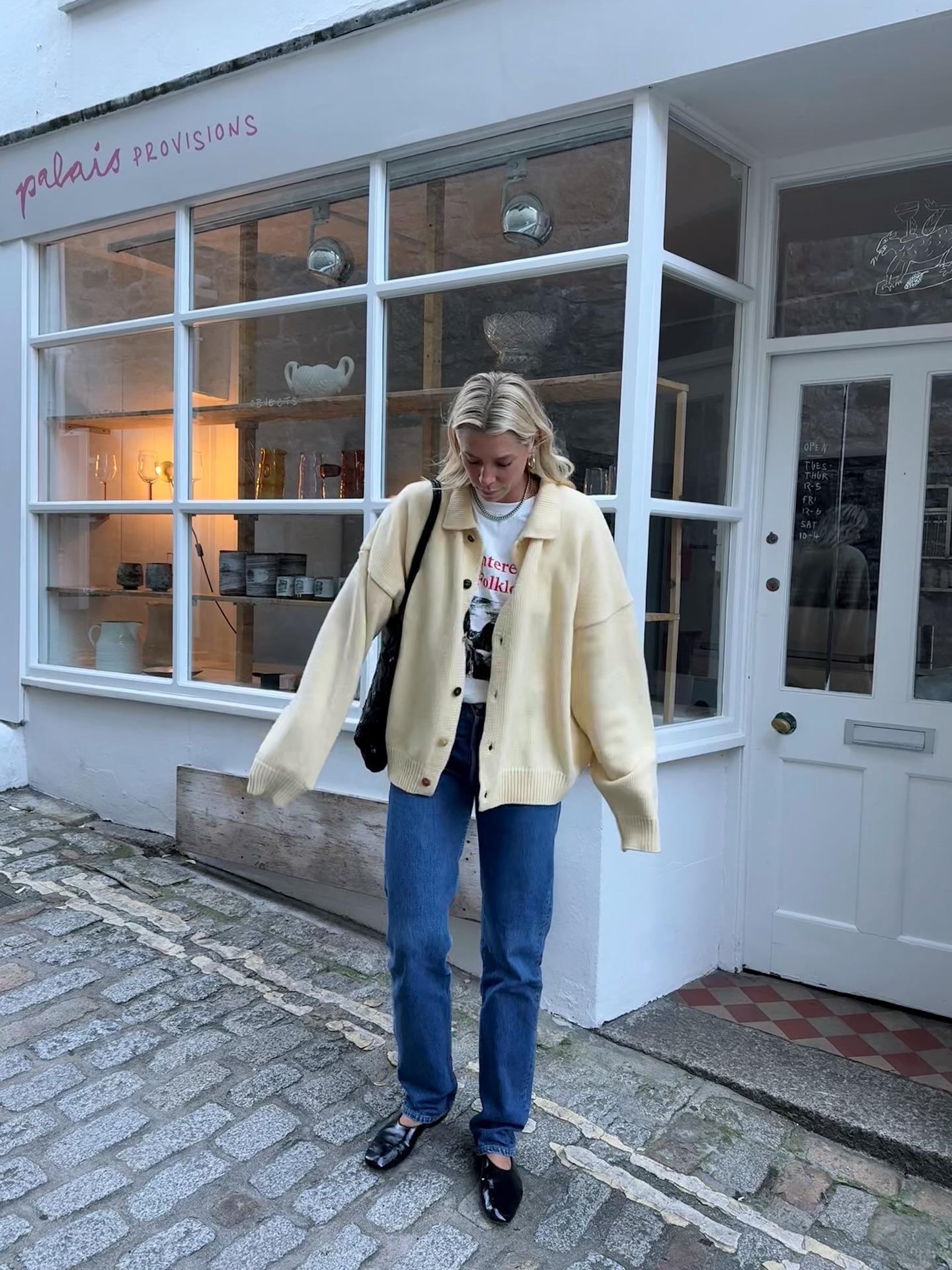 Influencer @lindseyholland_ wears a yellow collared cardigan with a graphic tee and jeans.