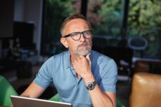 Mature man looking into the distance and thinking while using digital tablet on table at home.