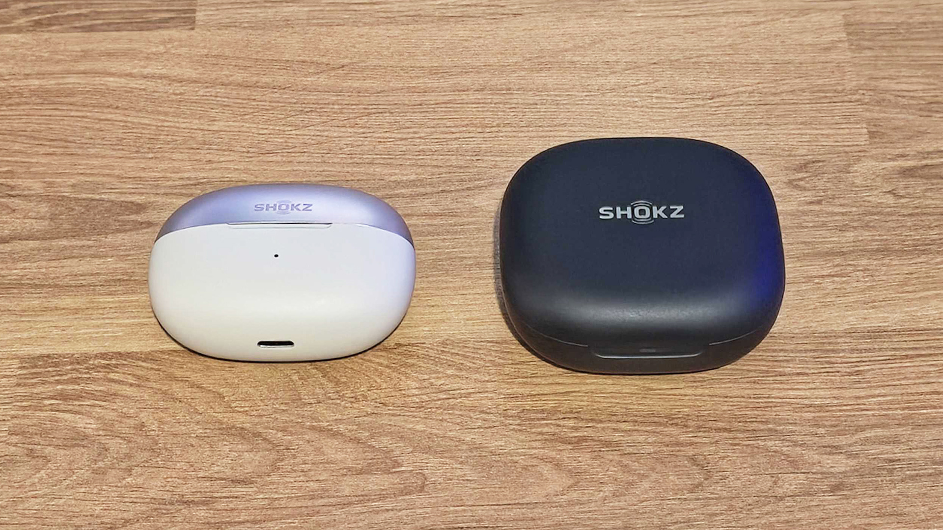 Shokz OpenDots One and OpenFit 2 Plus charging cases on desk