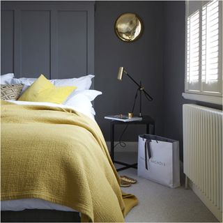 bedroom with dark grey wall and yellow throw