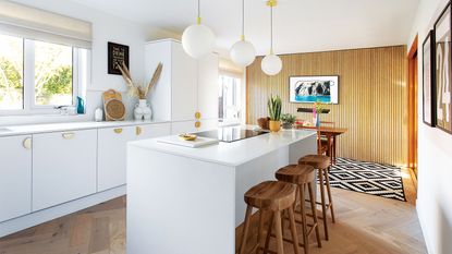 white kitchen with kitchen island and bar stools and wooden veneer feature wall