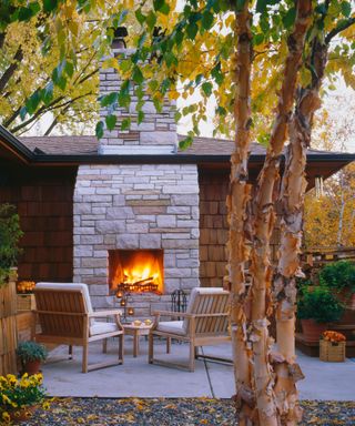 large stone outdoor fireplace on a paved backyard patio