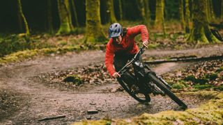 Female mountain biker leans low on berm