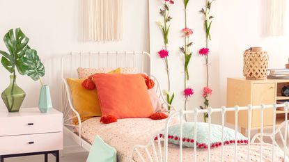 A bedroom with a bed with colorful pillows and a wall panel with flowers