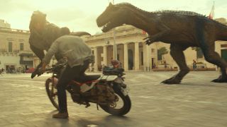 Scene from the movie Jurassic World Dominion. Here we see a man on a motorcycle trying to evade two large dinosaurs (an Allosaurus and Carnotaurus) whilst they chase him through the streets of Malta.