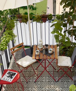 small balcony garden with patterned floor tiles and bistro set