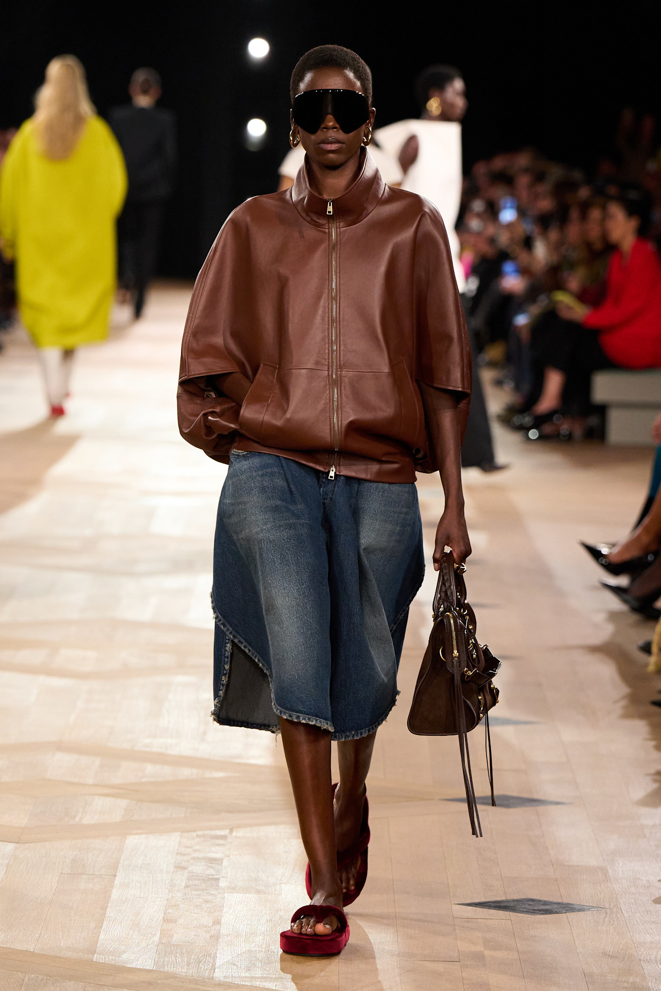 A Balenciaga runway model wearing denim Bermuda shorts.