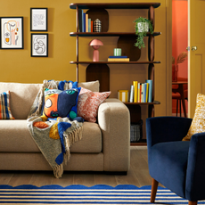 a colourful living room with sofa draped in throws and cushions