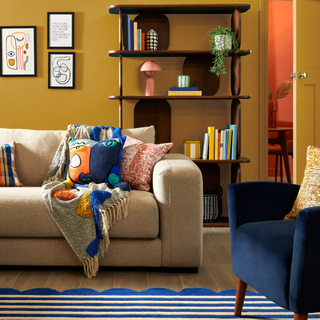 a colourful living room with sofa draped in throws and cushions