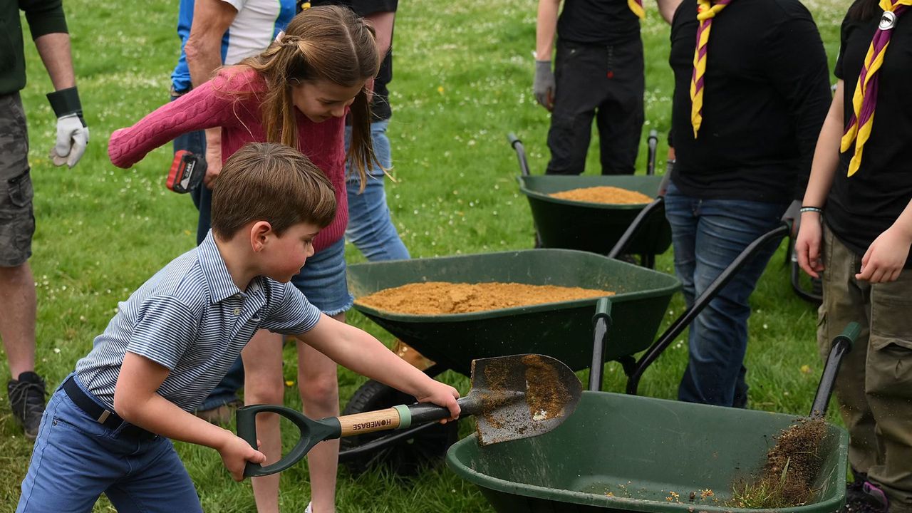 Princess Charlotte and Prince Louis shoveling dirt into a wheelbarrow