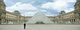 it must be heaven film still showing man outside louvre pyramid in paris