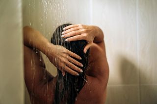 A woman washing her hair in the shower.