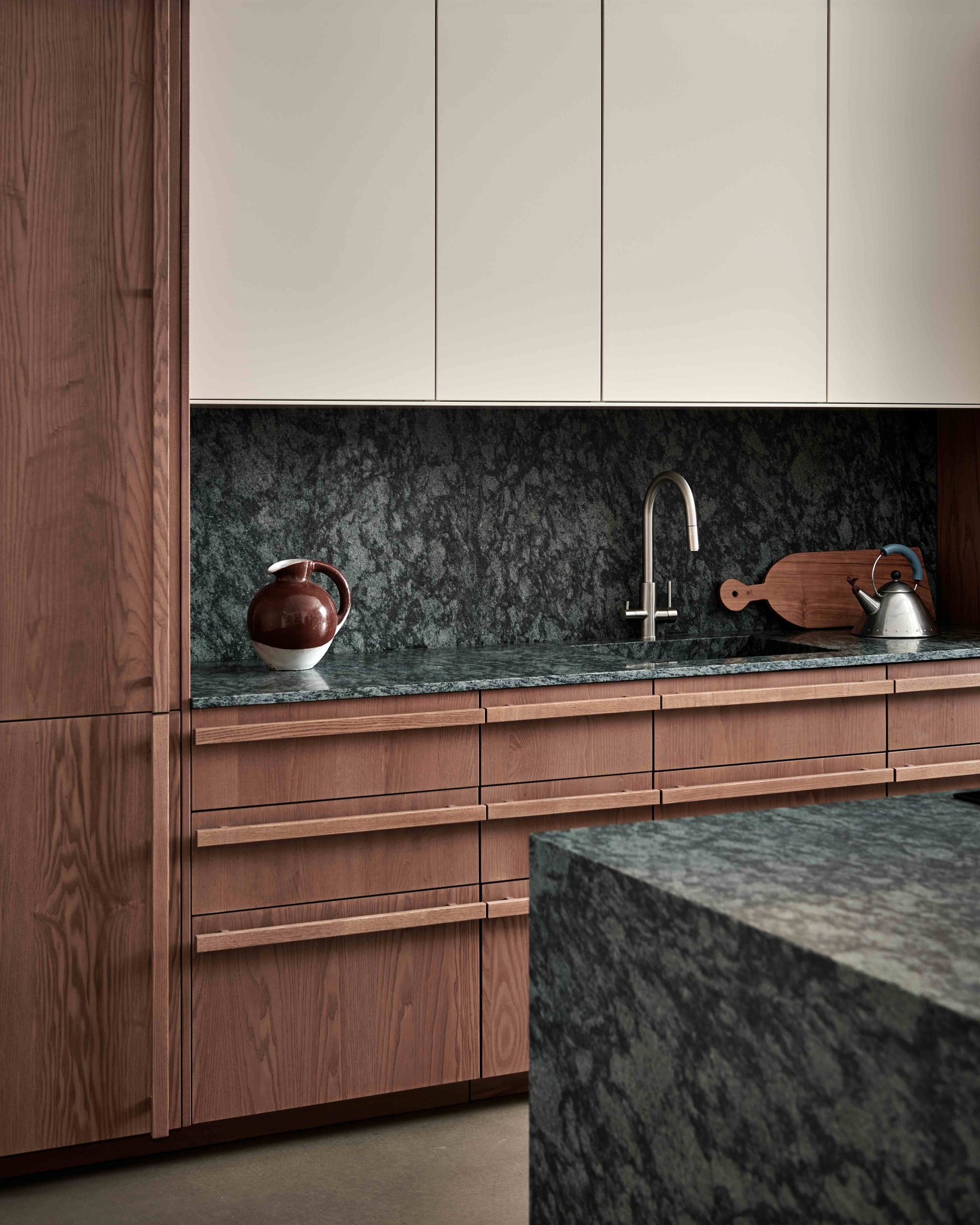 A minimalist kitchen with wooden cabinet fronts, granite worktops, and neutral upper cabinetry