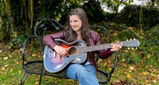 A portrait of Muireann Bradley playing her Waterloo acoustic guitar